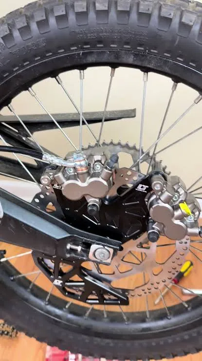 Dual rear calipers and bracket installed on a Sur-Ron Light Bee X rear wheel